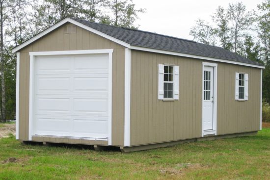 One of our garage sheds in Grovetown GA - Beige siding with white side and overhead doors and window with white shutters beneath dark gray roof