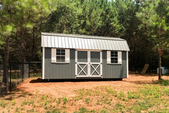 Gray and white Lofted Barn Max shed - painted gray wood siding with white-trimmed double doors corners and windows under gray metal roof