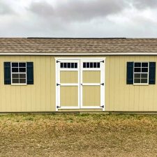 Beige Garden Shed Max with white trim and black shutters on cloudy day