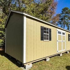 Beige 12x28 Garden Shed Max with white double doors and black shutters beneath blue sky