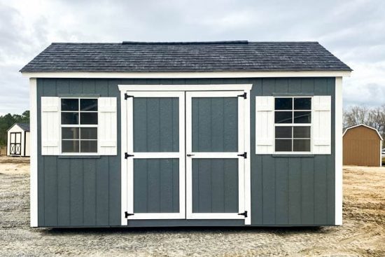 Gray 10x16 Garden Shed Max with white-trimmed double doors on open lot beneath cloudy sky