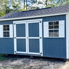 Front view of a gray 10x16 Garden Shed Max with white-trimmed double doors and shutters.