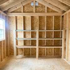 Interior of a wooden 10x16 Garden Shed Max featuring built-in shelves and open framing.