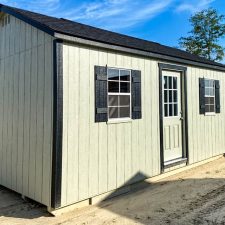 beige 12x20 Garden Shed Max with black window shutters and a single entry 9 lite door