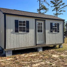 Front view of a beige 12x20 Garden Shed Max with black shutters and a single-entry door