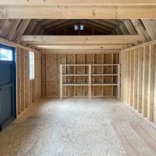 Interior of 12x28 Lofted barn Max with exposed wooden beams and visible shelving